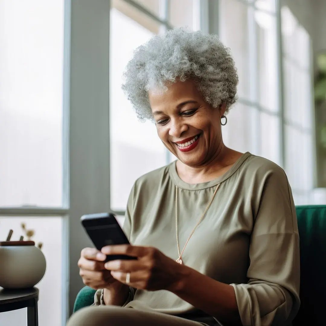 Woman with gray hair smiling while looking at smartphone